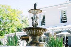 una estatua de una mujer en una fuente frente a un edificio en Pontac Manor Hotel & Restaurant, en Paarl