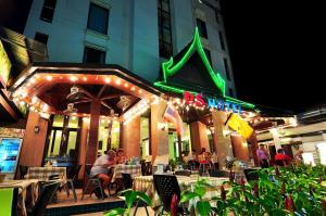 un ristorante con persone sedute ai tavoli e un'insegna al neon di PS Hotel Phuket Patong - SHA Plus a Patong Beach