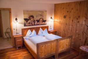 una camera da letto con un grande letto in legno con cuscini bianchi di Agriturismo Kabishof a Funes