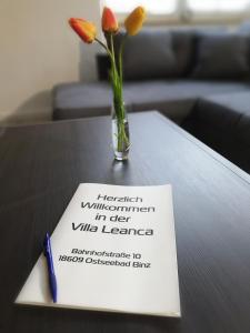 un vaso con fiori seduti su un tavolo con un cartello di Villa Leanca a Binz