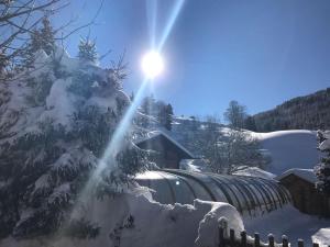 een zon schijnt achter een sneeuw bedekte boom met een trein bij Hôtel Chalet Alpage in La Clusaz