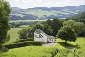 a small white house in the middle of a green field at Castle Peroch in Dunkeld