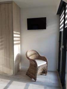 uma cadeira de vime numa sala com televisão em Dom Jan em Pobierowo
