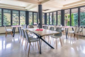 a row of tables and chairs in a room with windows at River Side Rooms in Elassona