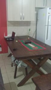 a wooden table in a kitchen with a laptop on it at 3 Kitnets in Rio das Ostras