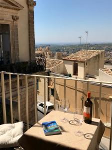 a table with a bottle of wine and glasses on a balcony at Town View in Noto