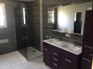 a bathroom with a shower and two sinks and a mirror at B&B de Saint Come de Fresné in Saint-Côme-de-Fresné