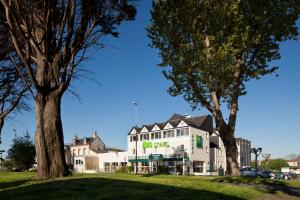 un edificio blanco con árboles delante de él en ibis Styles Ouistreham, en Ouistreham