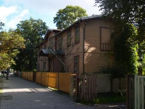 a brown house with a fence next to a street at Jurnieku nams in Liepāja