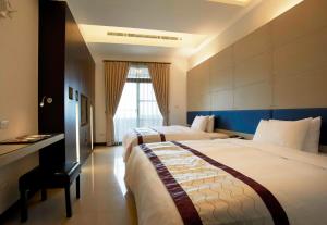 a hotel room with two beds and a desk at Master Hotel in Taipei