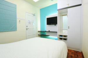 a bedroom with a white bed and a flat screen tv at The One Vacation Home in Malacca