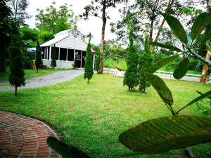 um jardim com um pavilhão ao fundo com um edifício em Saengcha Farm Resort em Prachin Buri