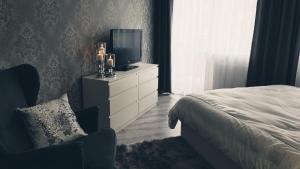 Dormitorio con cama y tocador con TV en Silver Apartaments en Piła