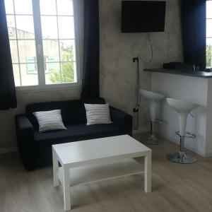 ein Wohnzimmer mit einem schwarzen Sofa und einem weißen Couchtisch in der Unterkunft Le Clos de Carinette in Châteauneuf-du-Pape