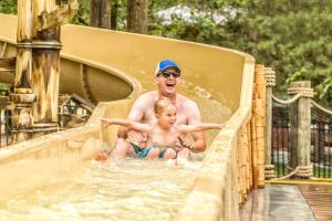 un hombre y un niño jugando en un tobogán en Still Waters Resort, en Branson