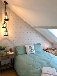 een slaapkamer met een blauw bed en een muur bij Lucarne Enchantée in Honfleur