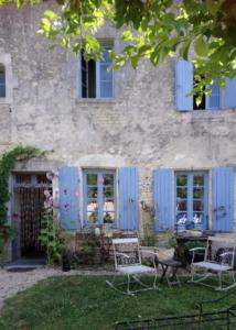 una casa con persianas azules y sillas en el patio en Le vieux Prieuré en Cressé