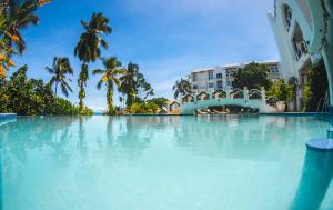 une grande piscine bordée de palmiers et un bâtiment dans l'établissement Madinat Al Bahr Business & Spa Hotel, à Zanzibar City