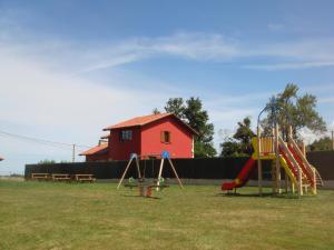 einen Spielplatz mit einem roten Haus im Hintergrund in der Unterkunft Los Picos de Tereñes in Tereñes