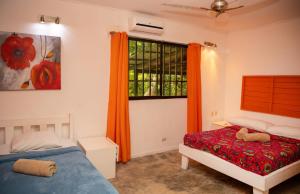 1 dormitorio con 2 camas y una ventana con cortinas de color naranja en Casa Cerise Beachfront, en Puerto Viejo