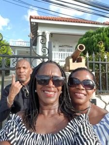 two women posing for a picture in front of a house at Paradise Palms Jamaica Vacation Rental in Montego Bay