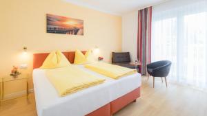 a bedroom with a large bed with yellow sheets at Pension Helios in Sankt Kanzian