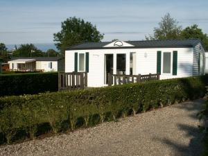 Maison blanche avec volets verts et terrasse couverte dans l'établissement Camping La Verte Prairie, à Forest-Montiers