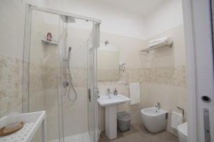 La salle de bains blanche est pourvue d'un lavabo et d'une douche. dans l'établissement B&B Galleria Principe di Napoli, à Naples