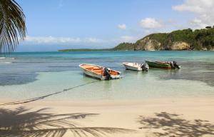 deux bateaux assis dans l'eau sur une plage dans l'établissement Studio Bleu Lagon dans résidence avec piscine, au Gosier