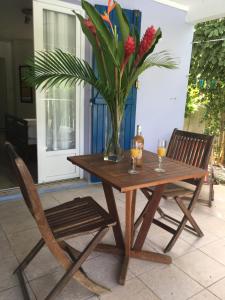 una mesa de madera con dos copas de vino y un jarrón con flores en Studio Bleu Lagon dans résidence avec piscine, en Le Gosier