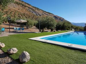 ein Pool in einem Garten mit Felsen im Gras in der Unterkunft Apartamentos Rurales La Dehesa del Acebuche in Jaén