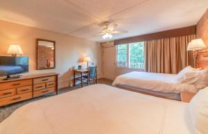 a hotel room with two beds and a flat screen tv at Mountain Chalet Snowmass in Snowmass Village