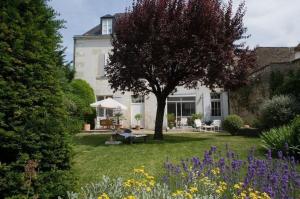 una casa con un árbol en un patio con flores en Chambres d'Hôtes Les Tilleuls, en Cognac