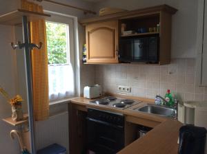 eine Küche mit einem Herd, einem Waschbecken und einem Fenster in der Unterkunft FeWo Wende in Heringsdorf