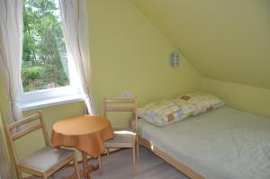 a bedroom with a bed and a chair and a window at Willa pod Brzozami in Niechorze