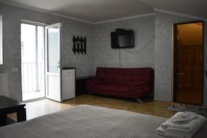 a living room with a red couch and a television at Tamarindi Guest House in Mtskheta