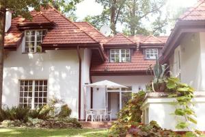 a white house with a table and an umbrella at Krzysin in Podkowa Leśna