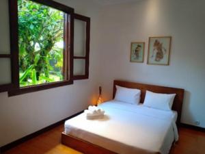 1 dormitorio con cama blanca y ventana en Villa Aquin en Solo