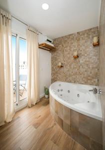 een badkamer met een bad en een groot raam bij La Casita del Atlántico in El Rompido