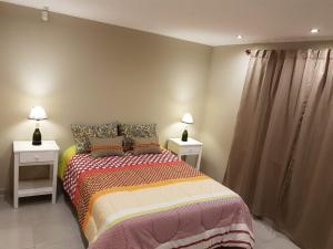 a bedroom with a bed with two night stands and two lamps at Cabañas Piedras de Tandil in Tandil