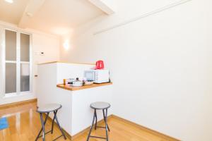 a kitchen with two stools and a microwave on a wall at Haneda Airport Apartment in Tokyo