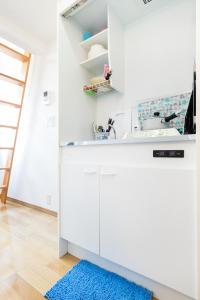 a kitchen with white cabinets and a blue rug at Haneda Airport Apartment in Tokyo
