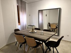 mesa de comedor con sillas y espejo grande en Apartamento SC Victoria, en Cáceres