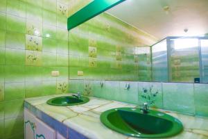 baño con espejo y 2 lavabos verdes en North Star Hostal Guayaquil, en Guayaquil