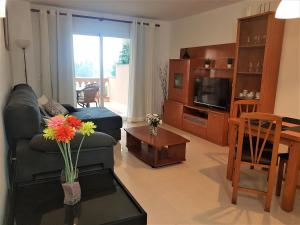 un soggiorno con divano e tavolo con fiori di Apartamento Serendipia Resort Cala Bona @Mallorca a Son Servera