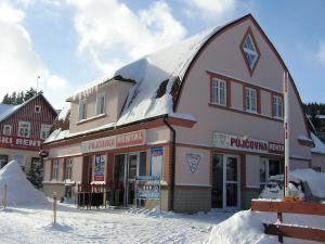a building with snow on the top of it at Apartmány Holiday Pec in Pec pod Sněžkou