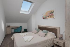 a white bedroom with a bed with a window at Sky Apartments in Čilipi