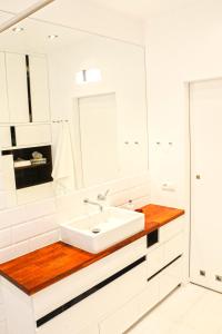 La salle de bains blanche est pourvue d'un lavabo et d'un miroir. dans l'établissement Apartament Relax Neptun Park, à Gdańsk