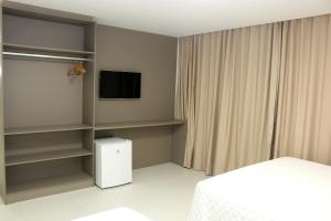um quarto com uma cama, uma televisão e prateleiras em Transcar Suítes em Aracaju