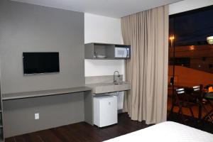 a hotel room with a sink and a tv at Transcar Suítes in Aracaju